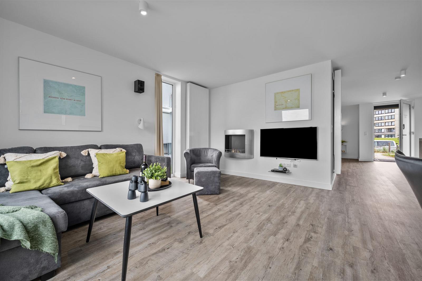 Wohnzimmer mit Sofa, Couchtisch und Fernseher. Holzboden und moderne Einrichtung.