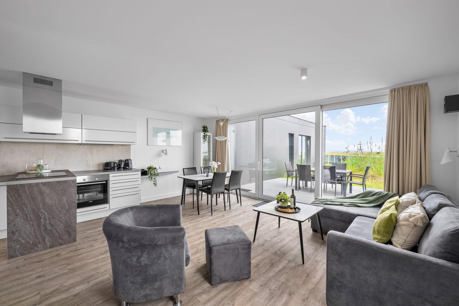 Wohnküche mit Essbereich und Terrasse. Modern eingerichtet mit grauer Couch und Sitzgruppe.