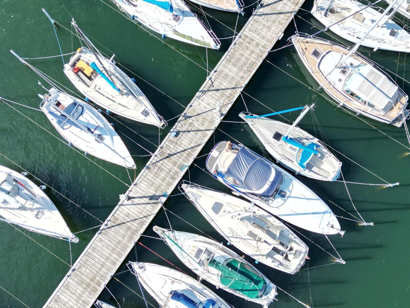 Aerial view of boats docked at a wooden pier in calm water.