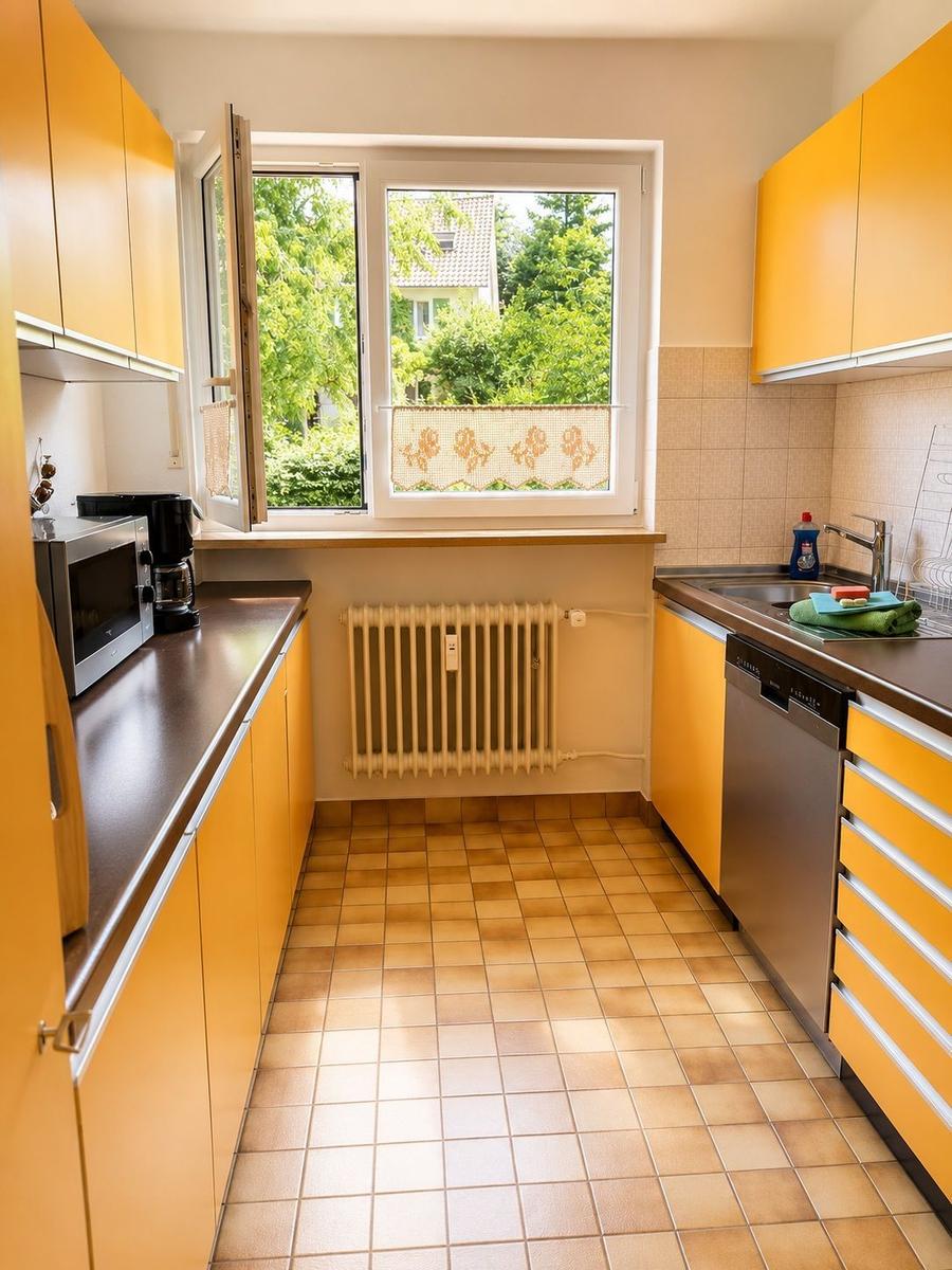 Küche mit gelben Schränken, Fenster und Waschbecken