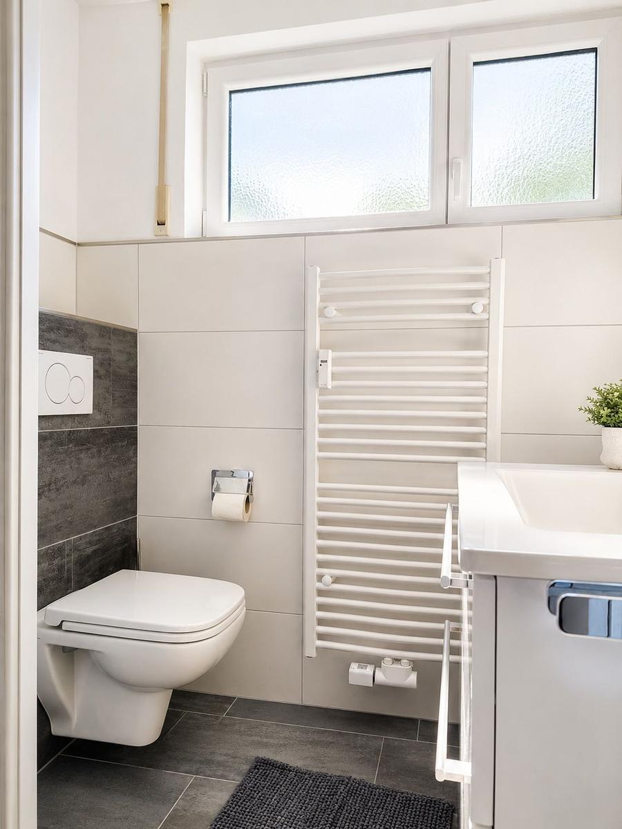 Badezimmer mit Toilette, Waschbecken und Heizkörper an der Wand.