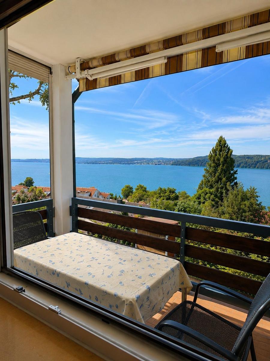 Balkon mit Tisch und Stühlen bietet Blick auf See und Landschaft.