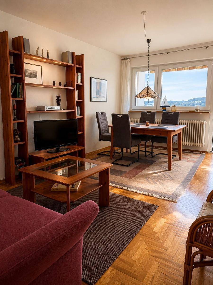 Wohn- und Essbereich mit Holzmöbeln, Fernseher und Blick auf die Berge.