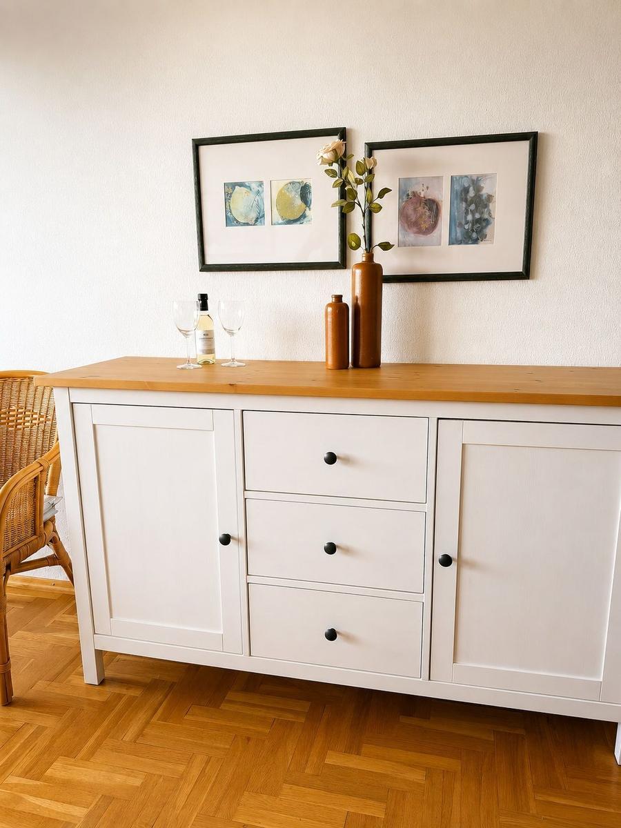 Weißer Sideboard mit Holzoberfläche, zwei Bilder und Dekoration.