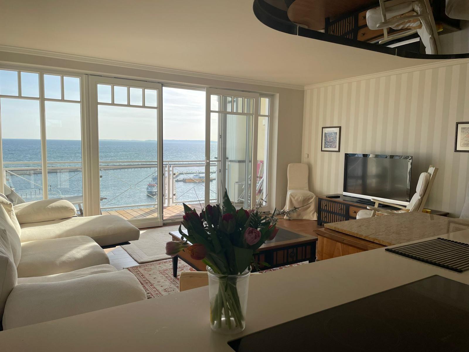 Wohnzimmer mit Meerblick, Sofa, Fernseher und Kücheninsel.