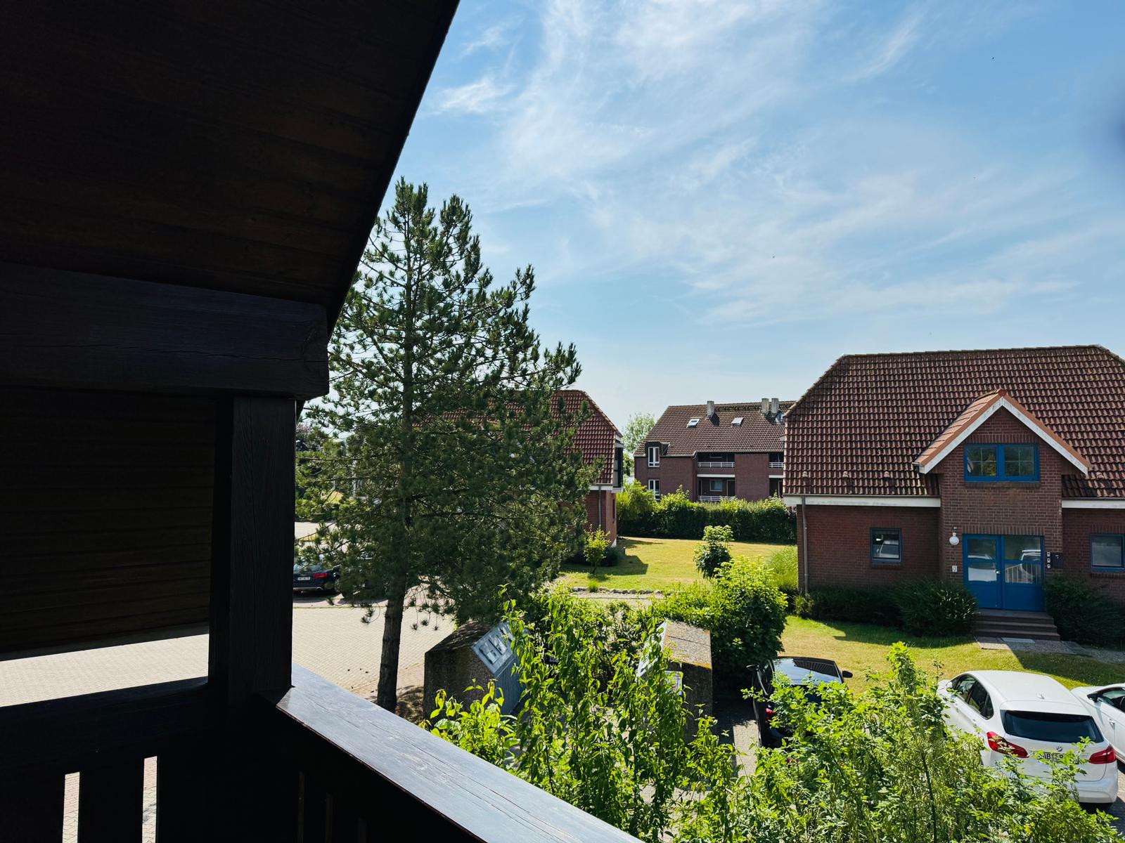 Blick von Balkon auf grünen Garten und rote Dächer