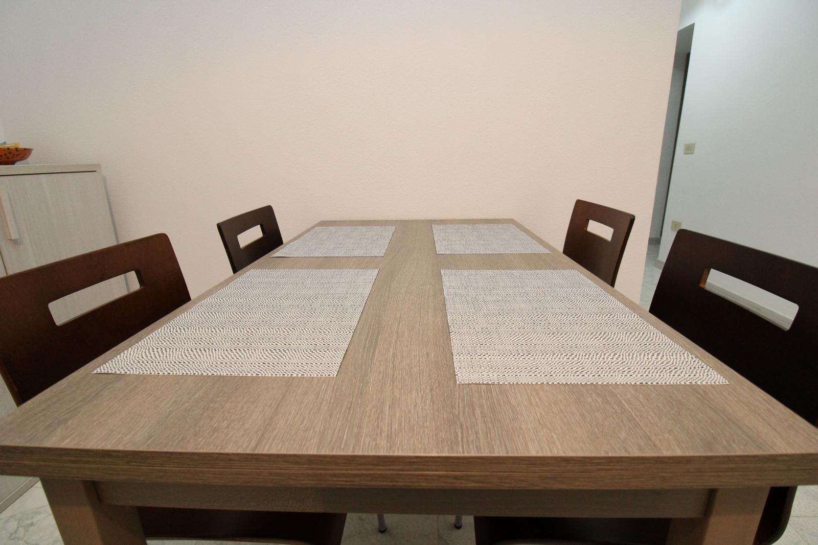 Esstisch mit vier Stühlen und Tischsets.
