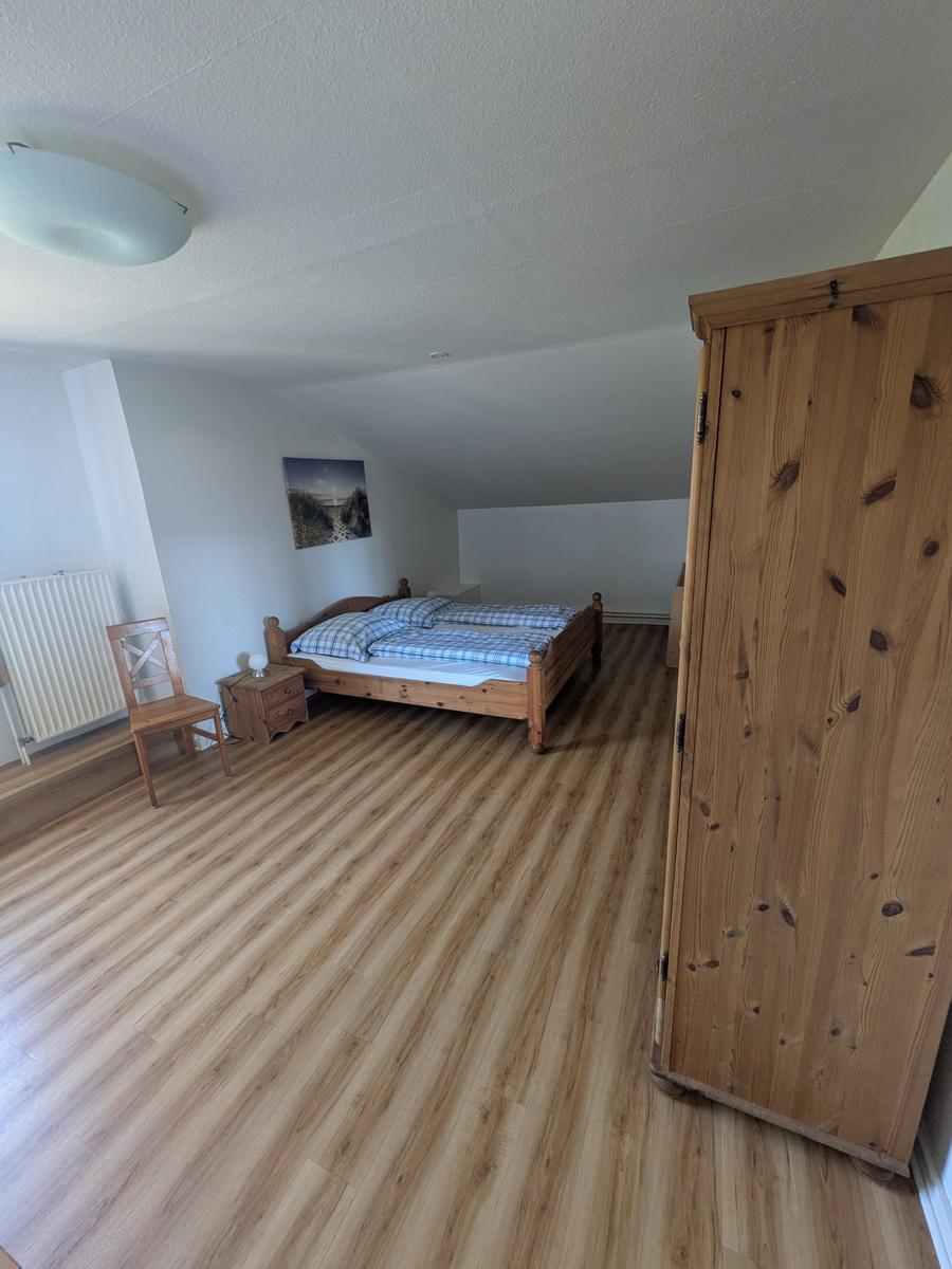 Schlafzimmer mit Holzbett, Kleiderschrank und Holzfußboden.