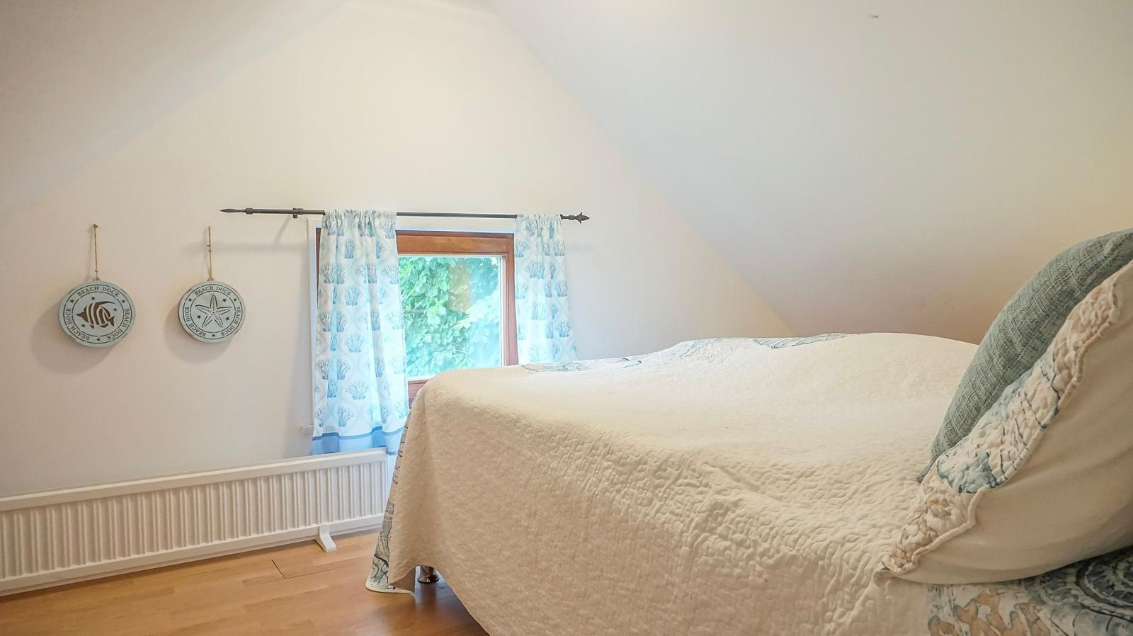 Schlafzimmer mit Bett, Fenster und Wanddekoration.