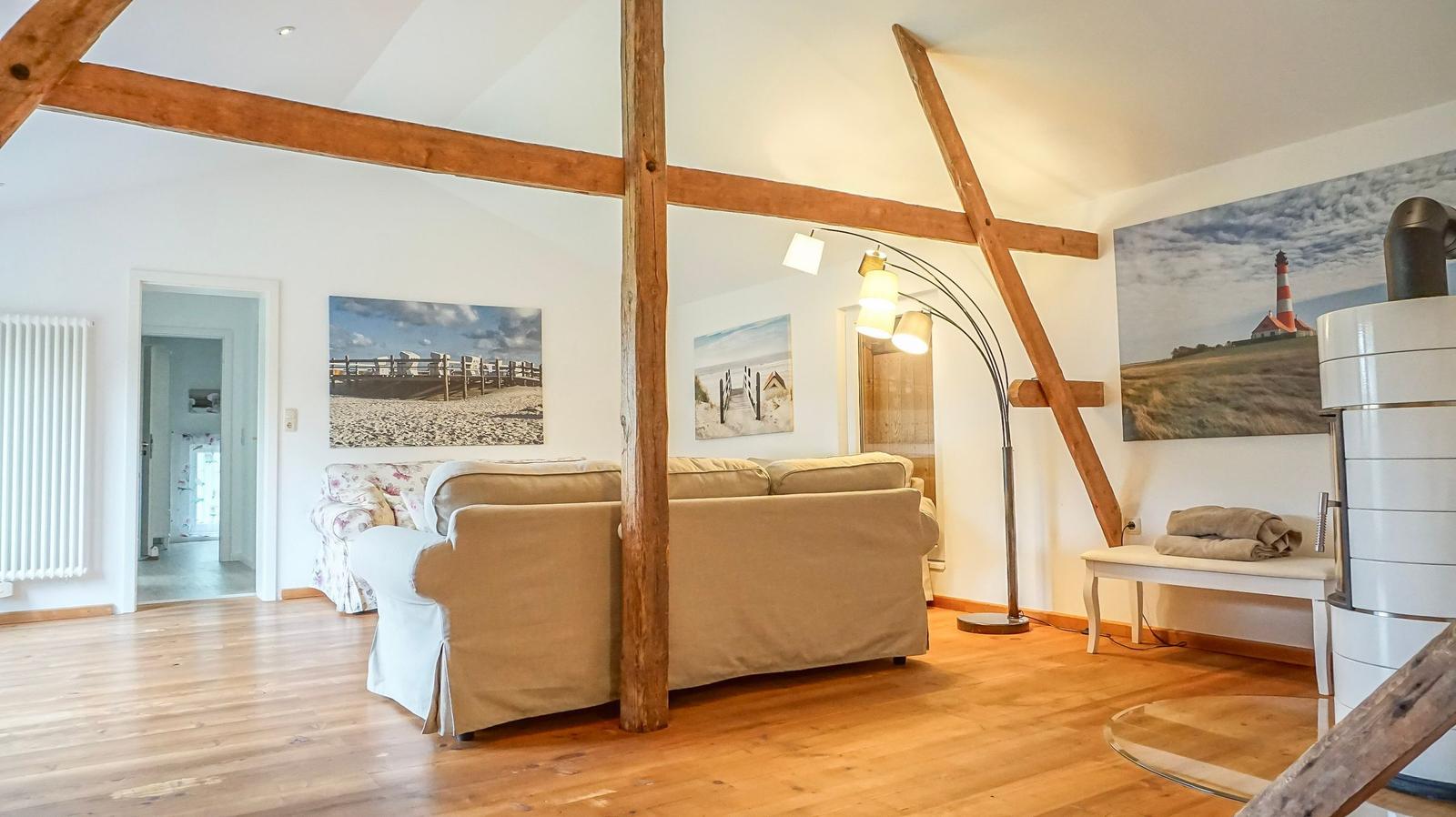 Wohnzimmer mit Holzbalken, Sofa, Bodenheizung und Wandbildern