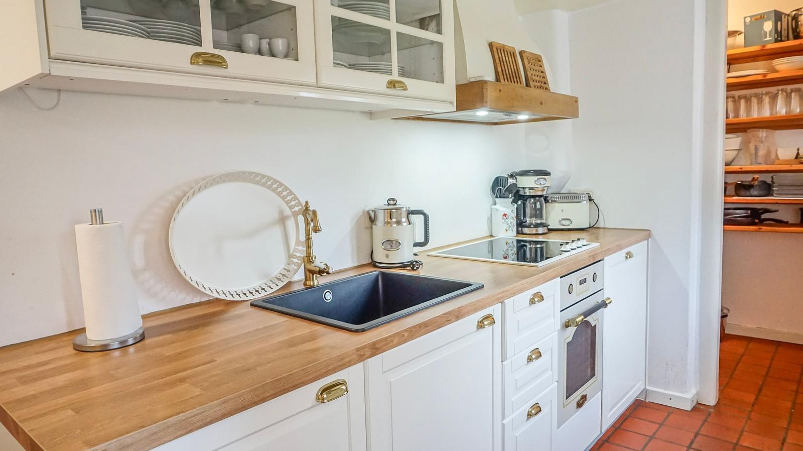 Küche mit Holz Arbeitsplatte, weißen Schränken und Edelstahl Spüle.