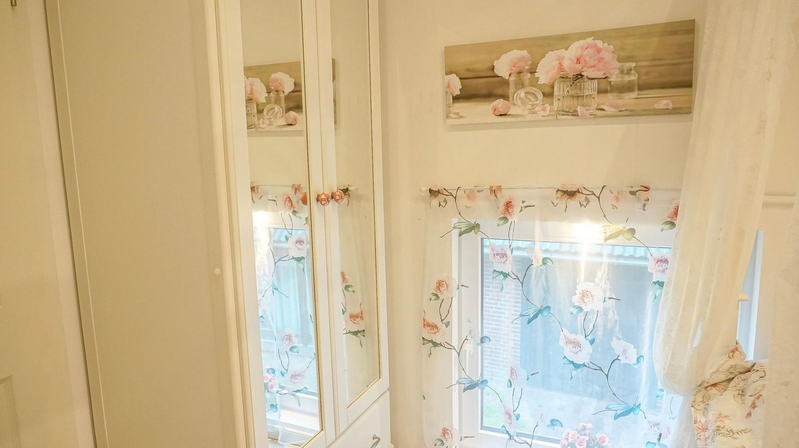 Schrank mit Spiegeltüren und Fenster mit floralen Vorhängen