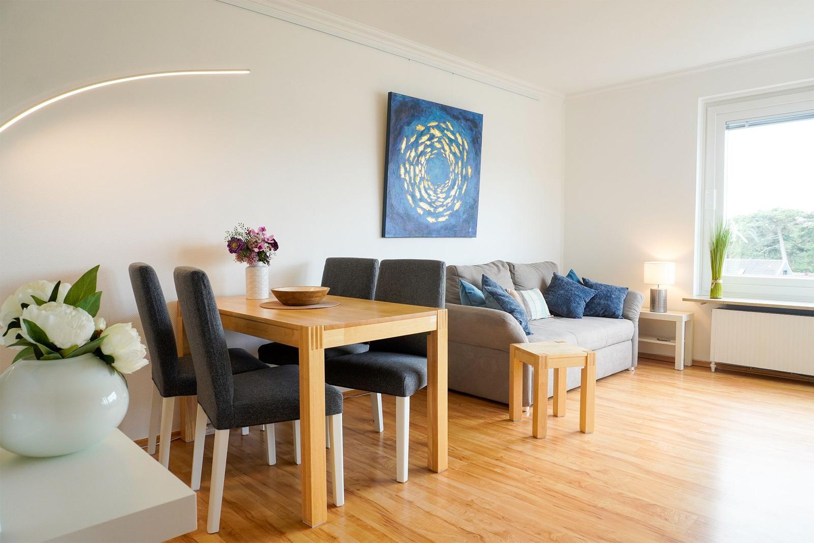 Ein Essbereich mit Tisch und Stühlen neben einem Sofa mit Kissen.