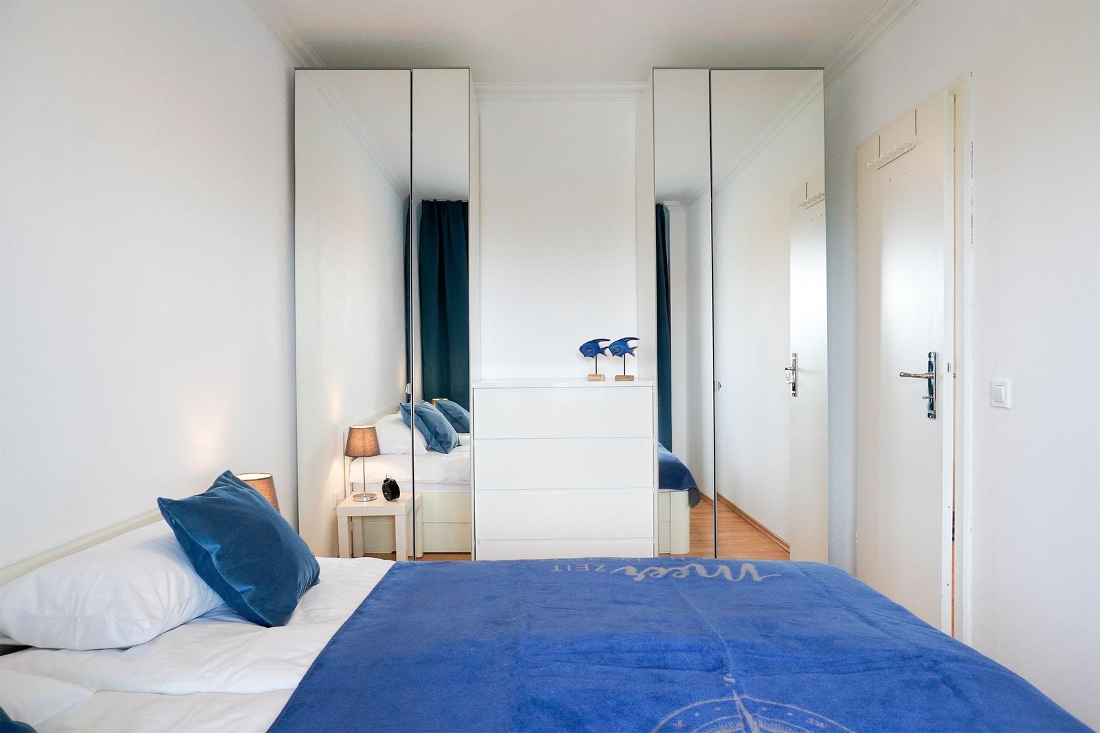 Schlafzimmer mit Bett, Kleiderschrank und Nachttisch.