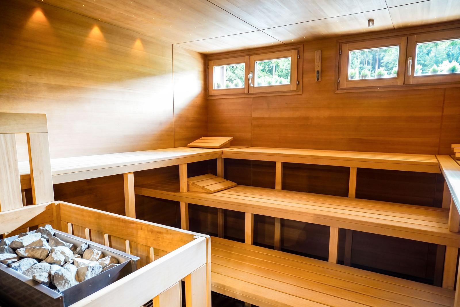 Holzsauna mit mehreren Sitzbänken und Fenstern zur Aussicht.