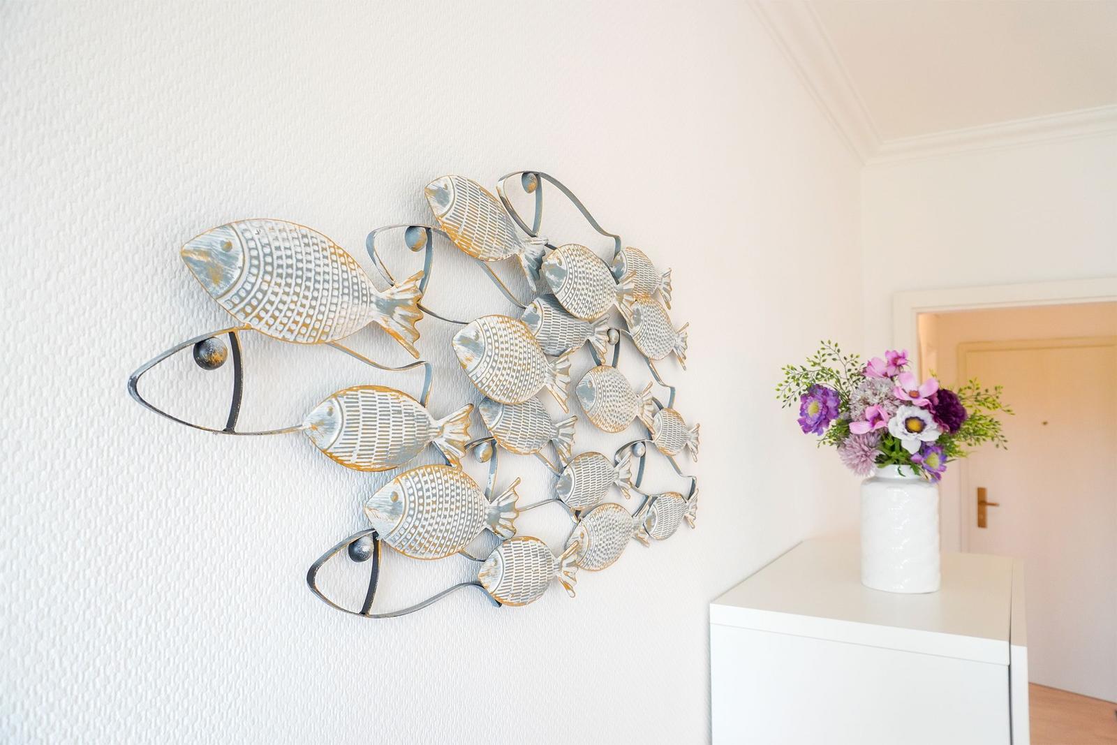 Wanddekoration mit Fischmotiven und Blumen auf einem Tisch