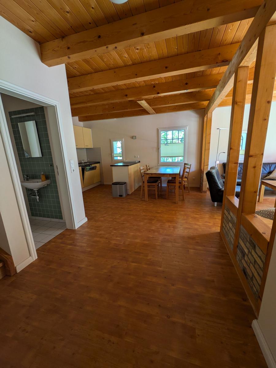Haus mit Holzboden, Essbereich, Küche und Bad im Hintergrund.