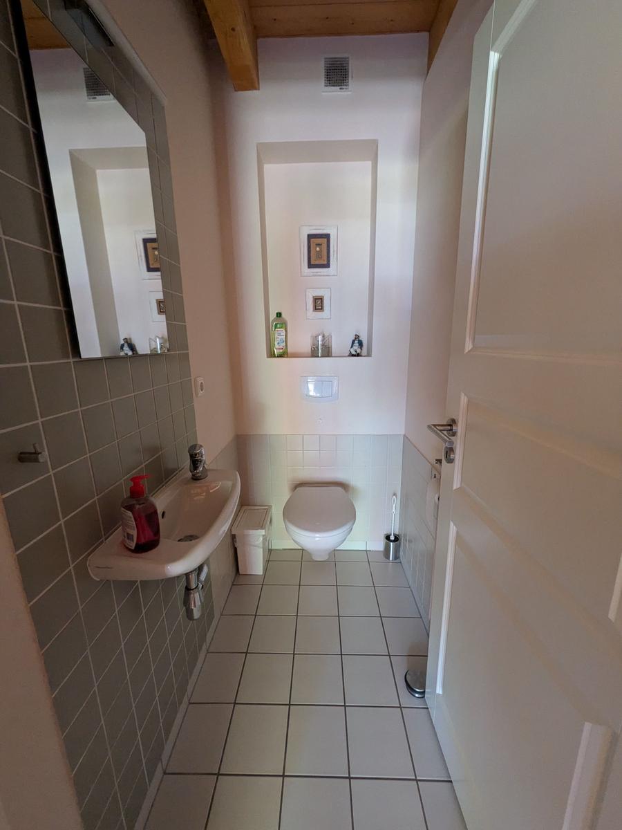 Badezimmer mit Waschbecken, Toilette und Spiegel an der Wand.
