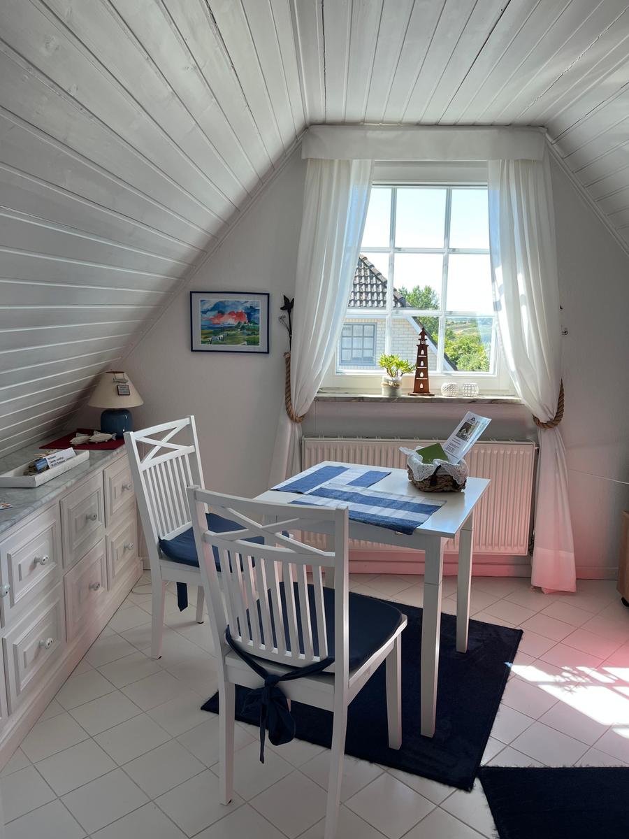 Dachbodenraum mit Tisch, zwei Stühlen und Fenster mit Blick nach draußen.