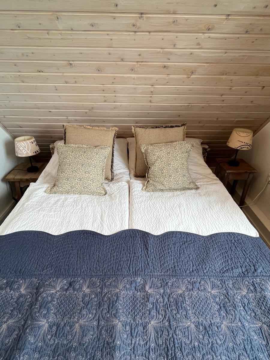 Doppelbett mit blauer Decke und Kissen unter Holzwand