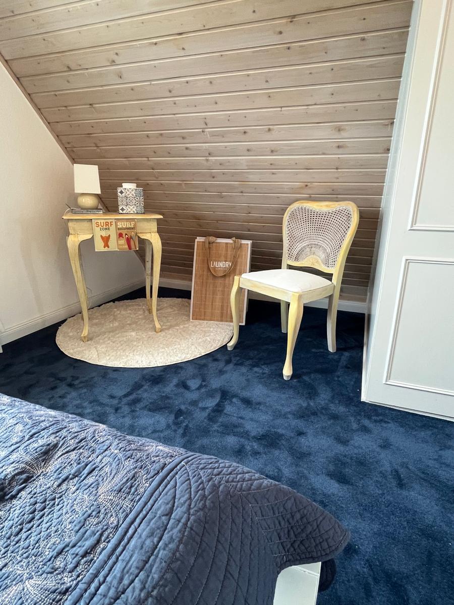 Schlafzimmer mit Holzwand, Stuhl und Tisch auf blauem Teppich