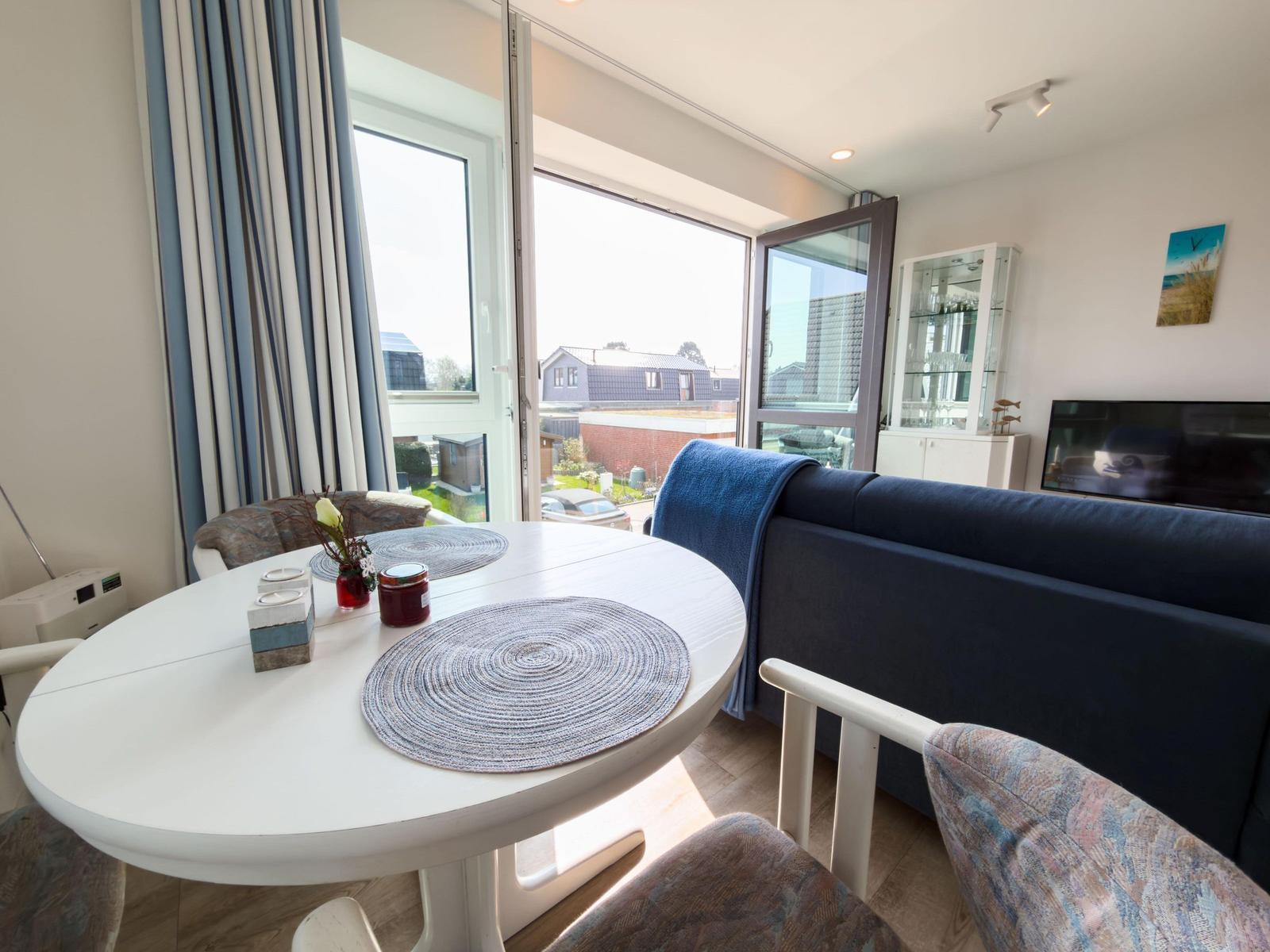 Round table with placemats and sofa in living area with view of the street.