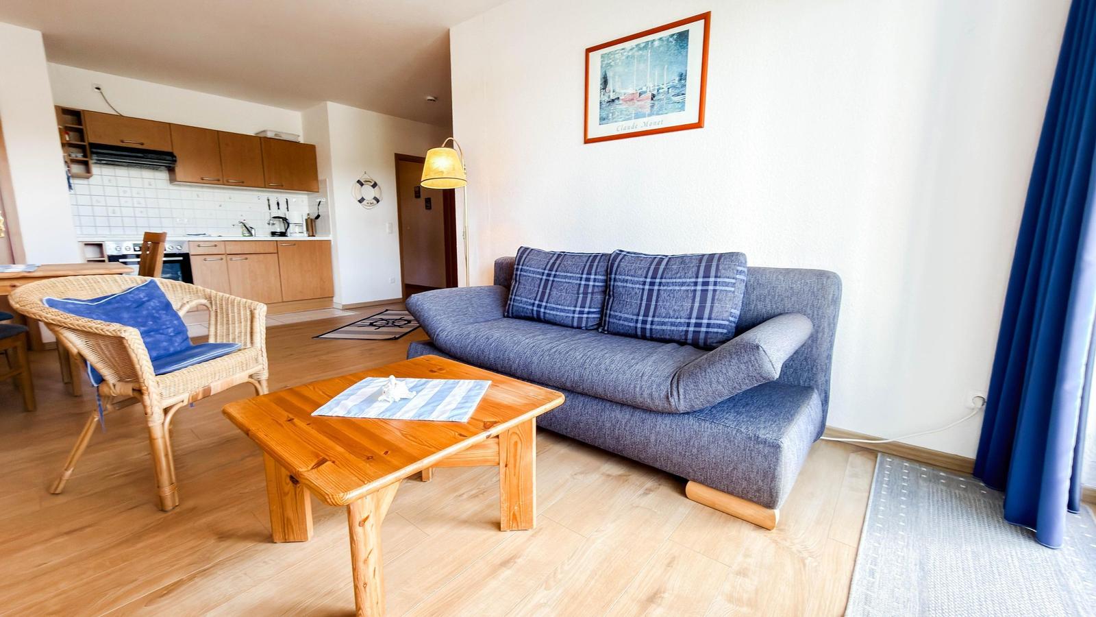 Wohnbereich mit Sofa, Tisch und Küchenbereich im Hintergrund.