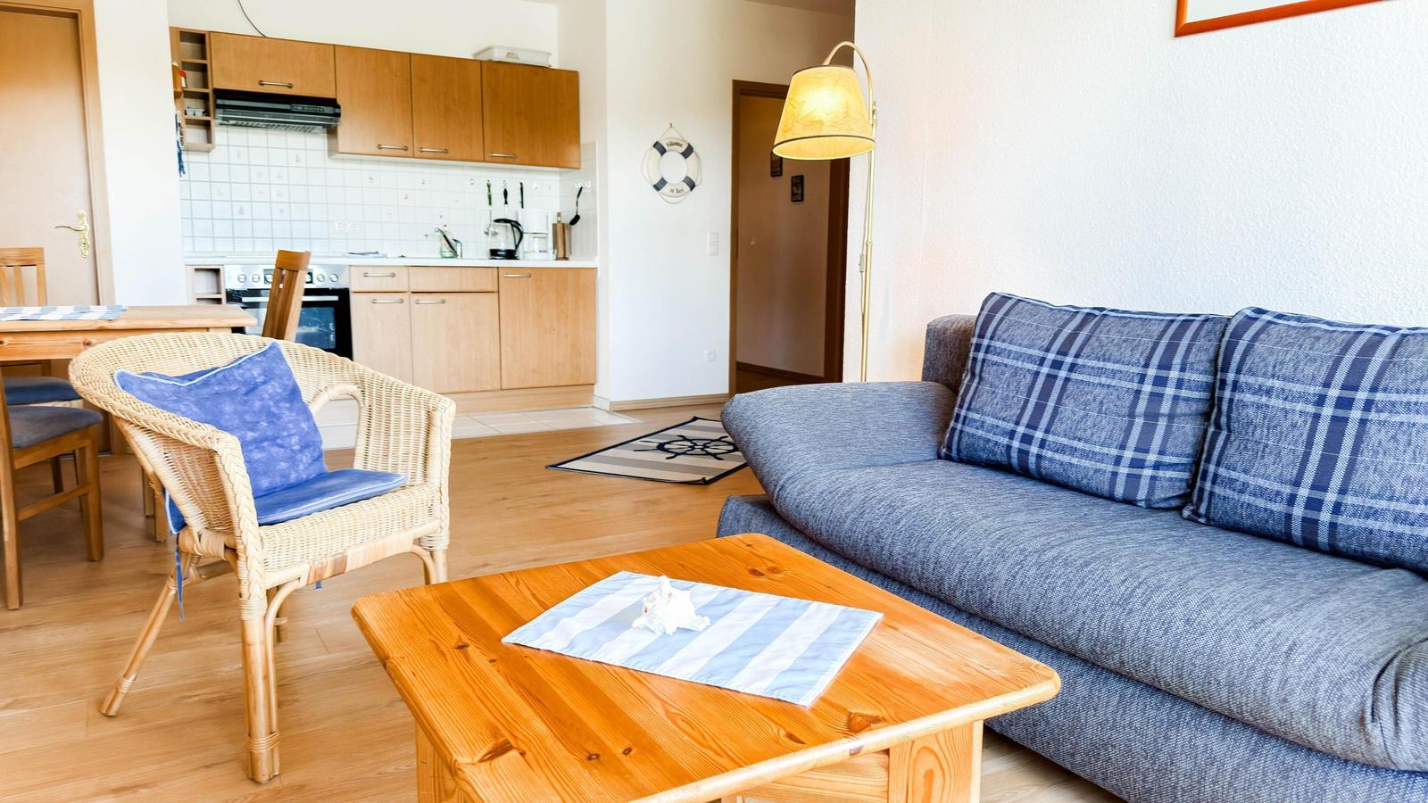 Wohnzimmer mit Sofa, Couchtisch und Küchenbereich im Hintergrund.