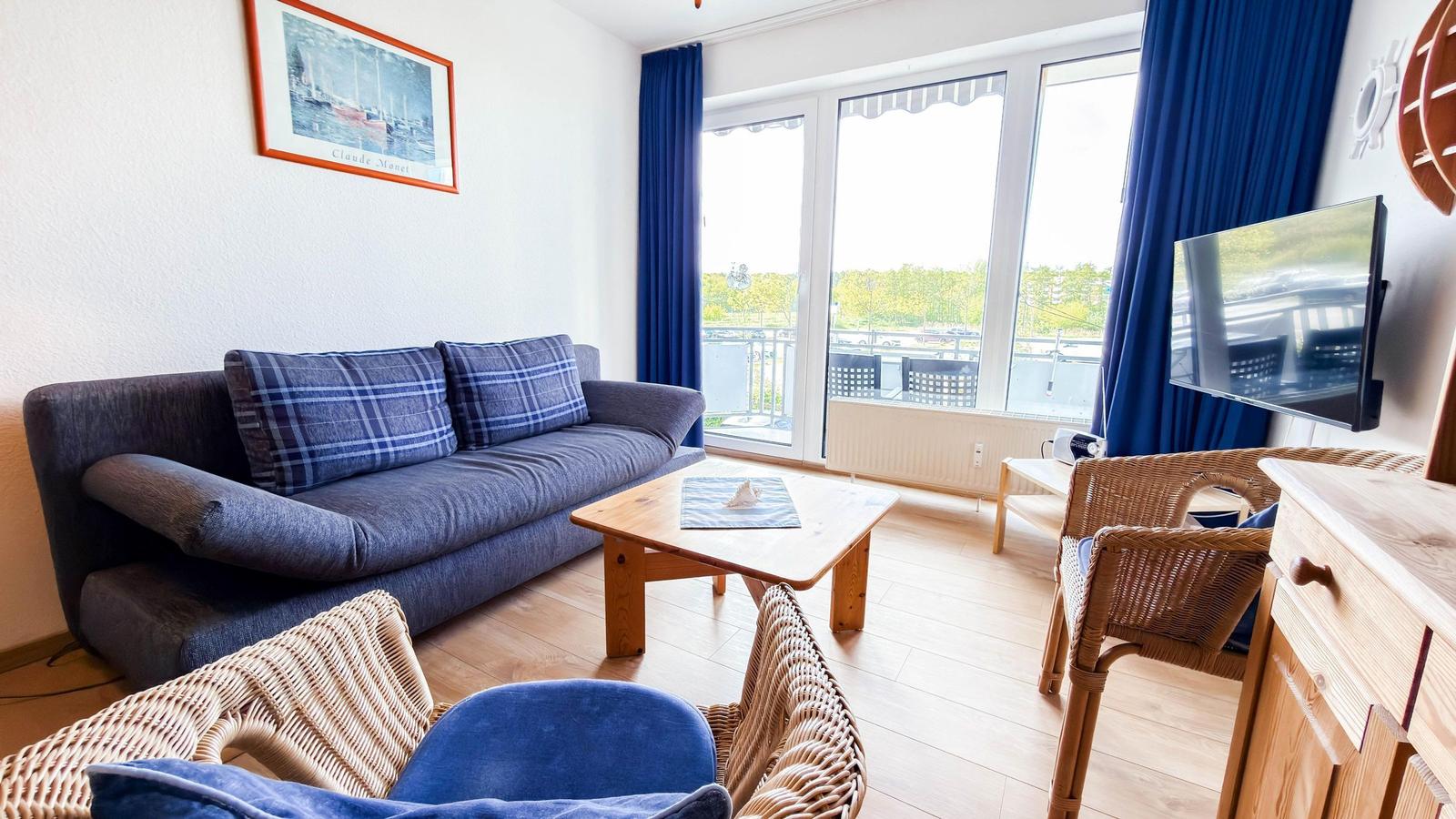 Wohnzimmer mit Sofa, Tisch und TV. Durchgang zur Terrasse mit Blick.