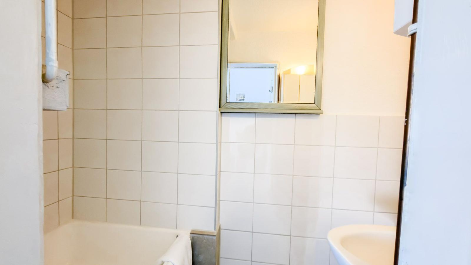 Badezimmer mit Badewanne, Spiegel und Waschbecken.