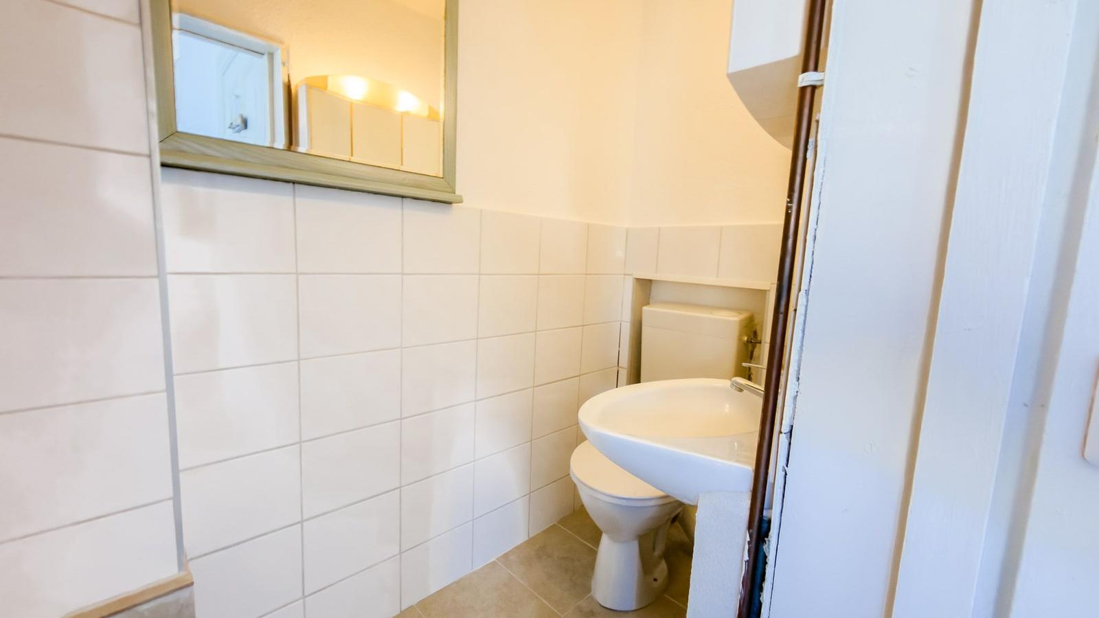 Badezimmer mit Toilette, Waschbecken und Spiegel an der Wand.