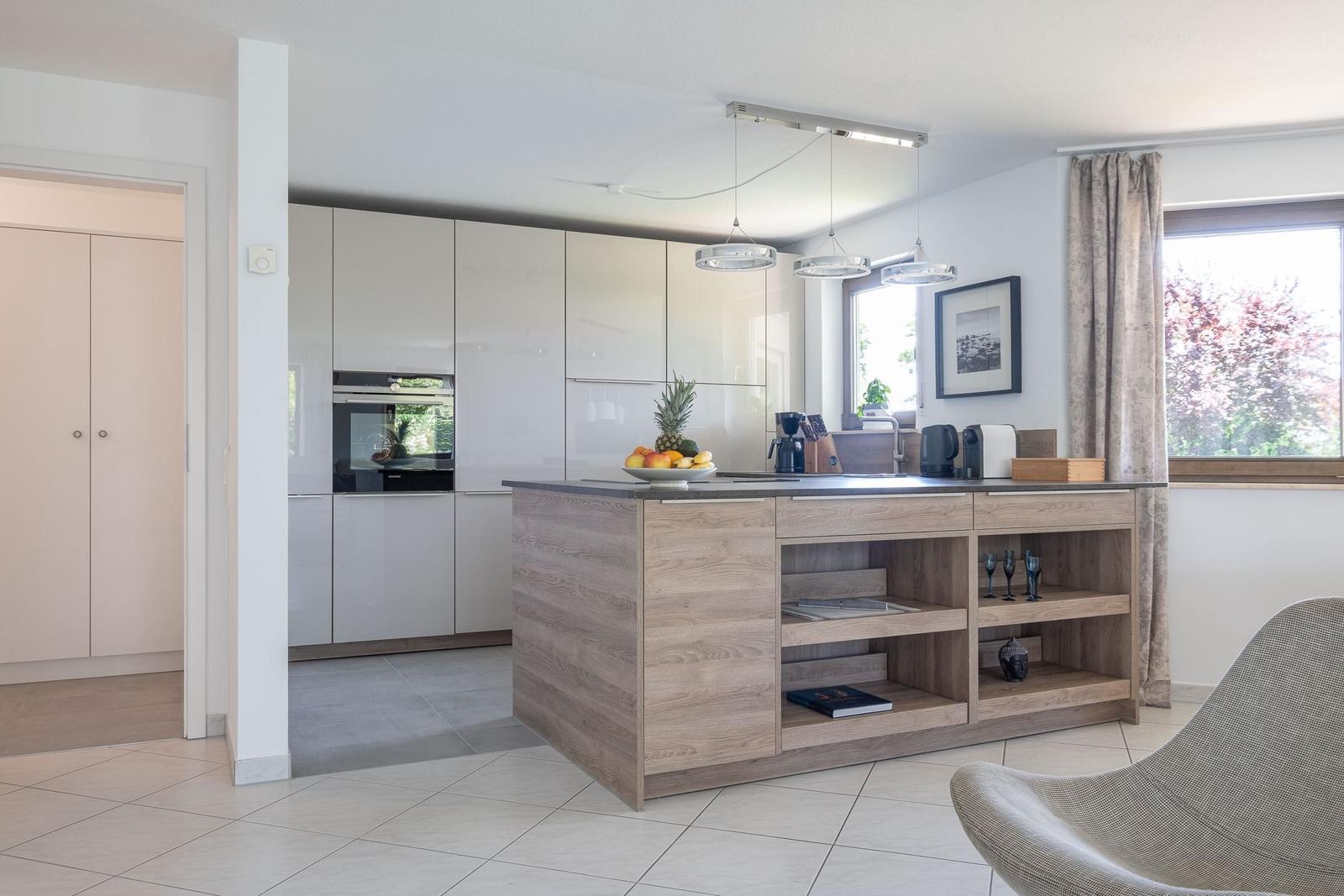 Moderne Küche mit Holzinsel und integriertem Ofen. Fenster mit Vorhang und Sitzgelegenheit.
