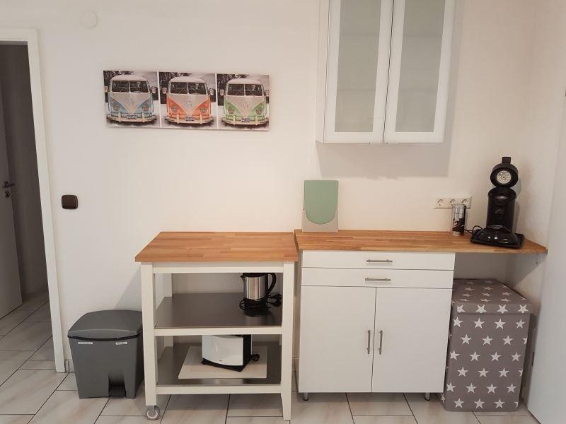 Küchenbereich mit Arbeitsfläche, Schrank und Kaffeemaschine.