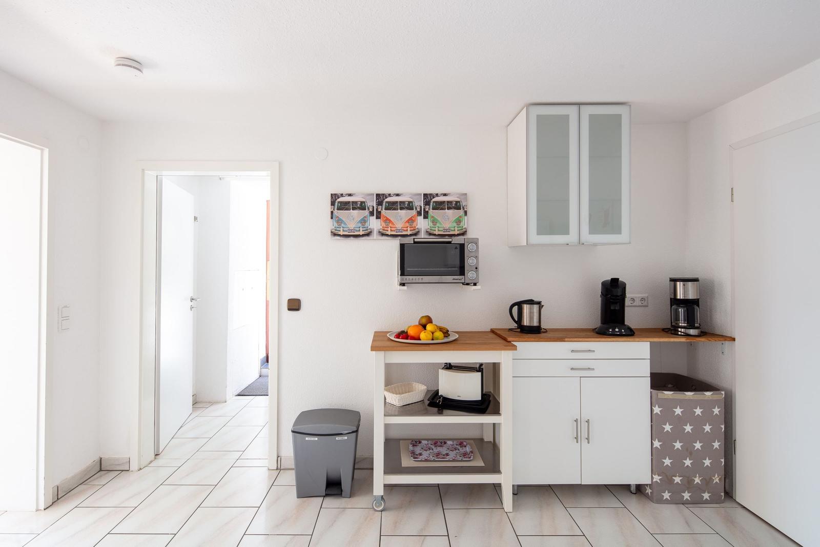 Küche mit Arbeitsplatte, Kühlschrank, Kaffeemaschine und Obstschale.