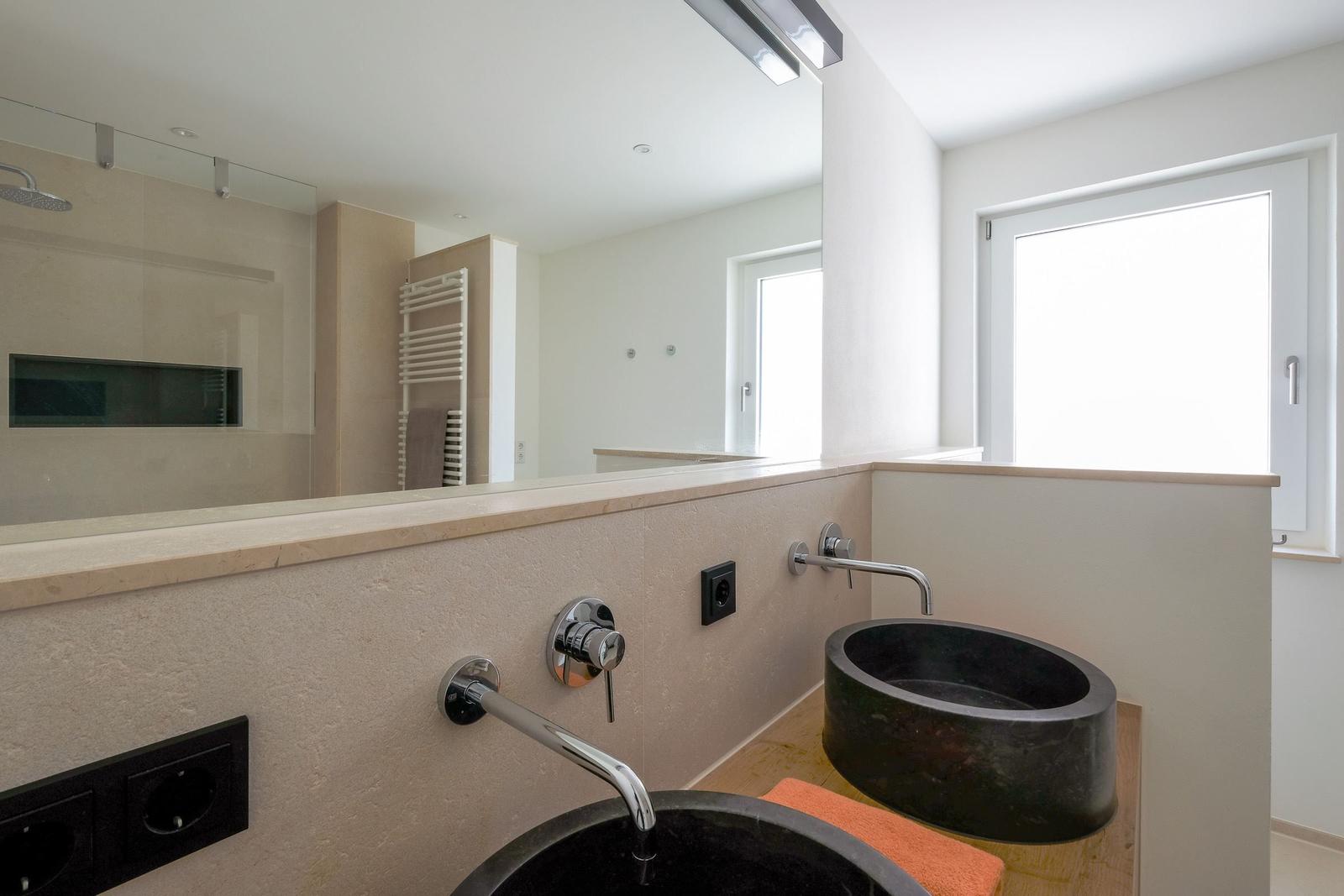 Badezimmer mit zwei schwarzen Waschbecken, Spiegel und Fenster.