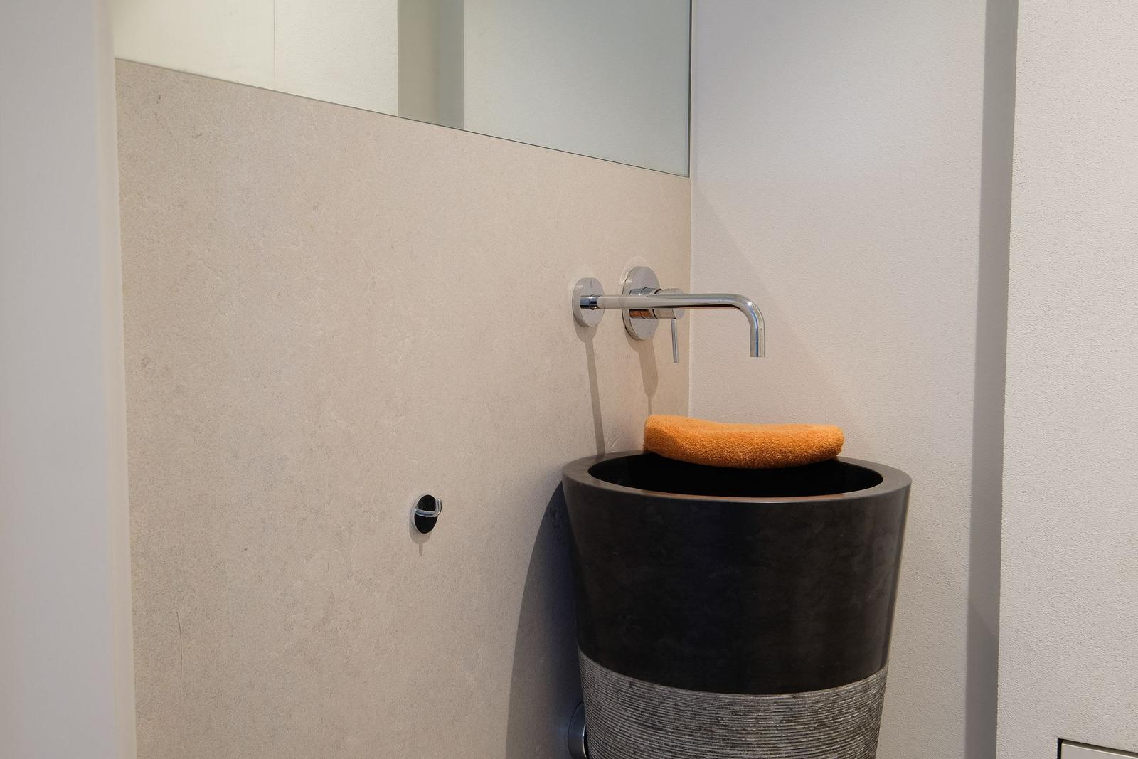 Dusche mit schwarzer Sitzbank und orangefarbenem Handtuch