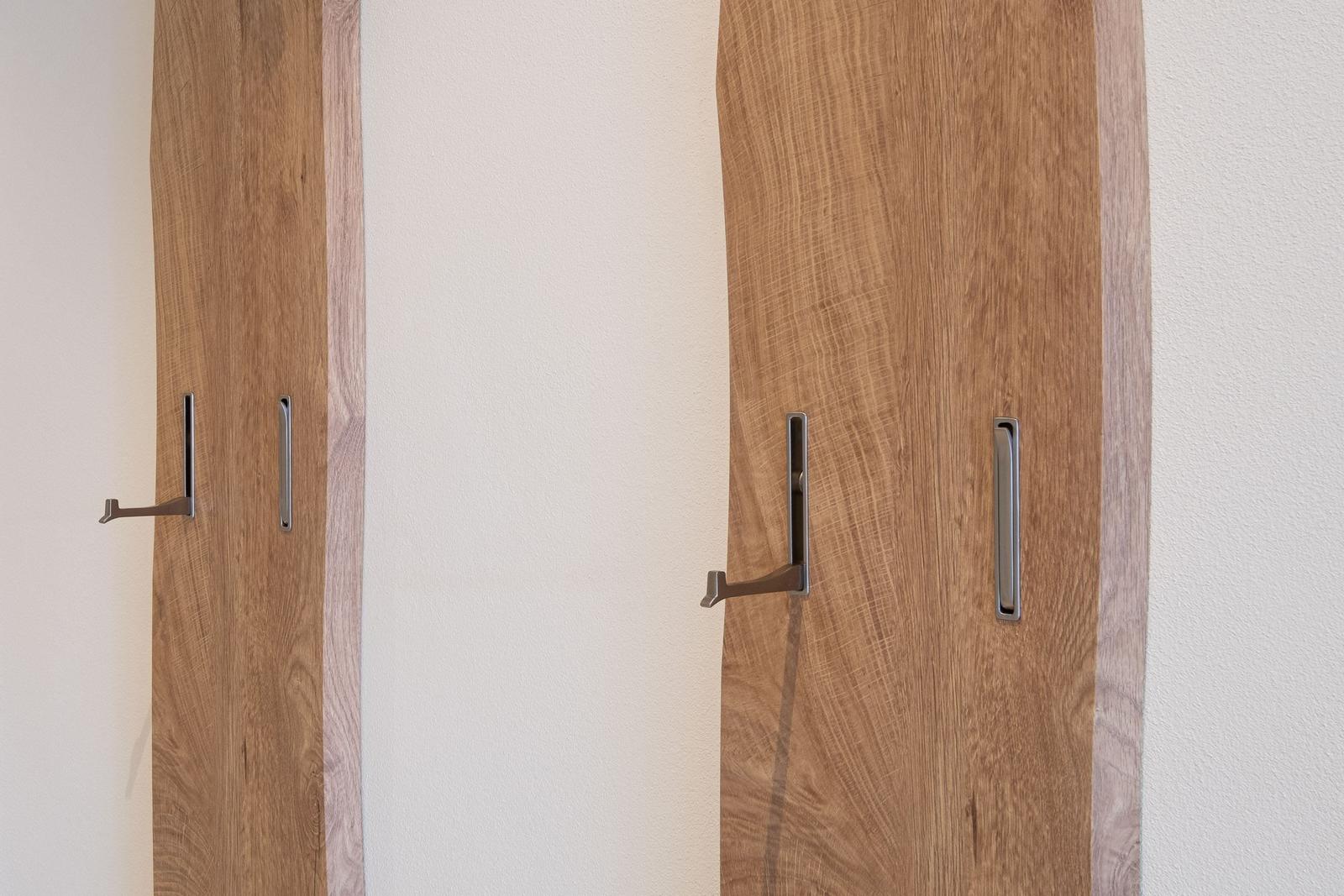 Zwei Holztüren mit metallischen Griffen an einer weißen Wand.