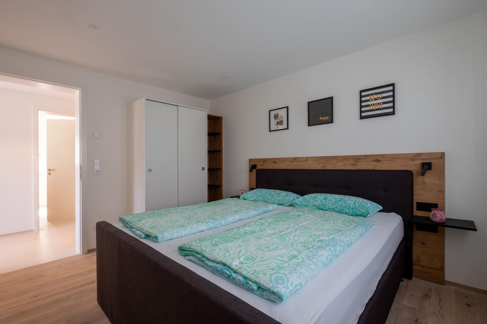 Schlafzimmer mit Doppelbett, Kleiderschrank und Wandbildern.