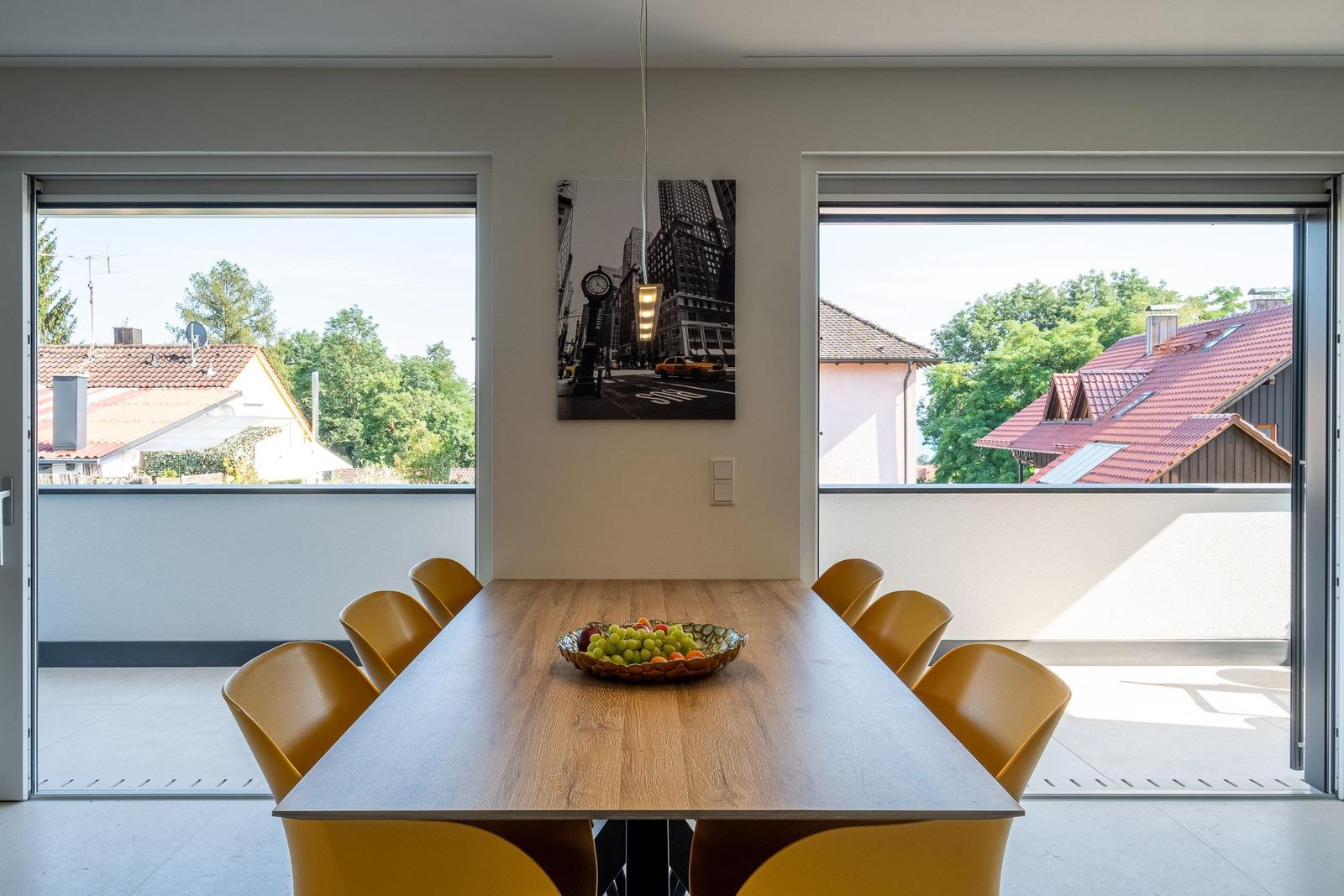 Esszimmer mit Holztisch, gelben Stühlen und Blick auf Balkon