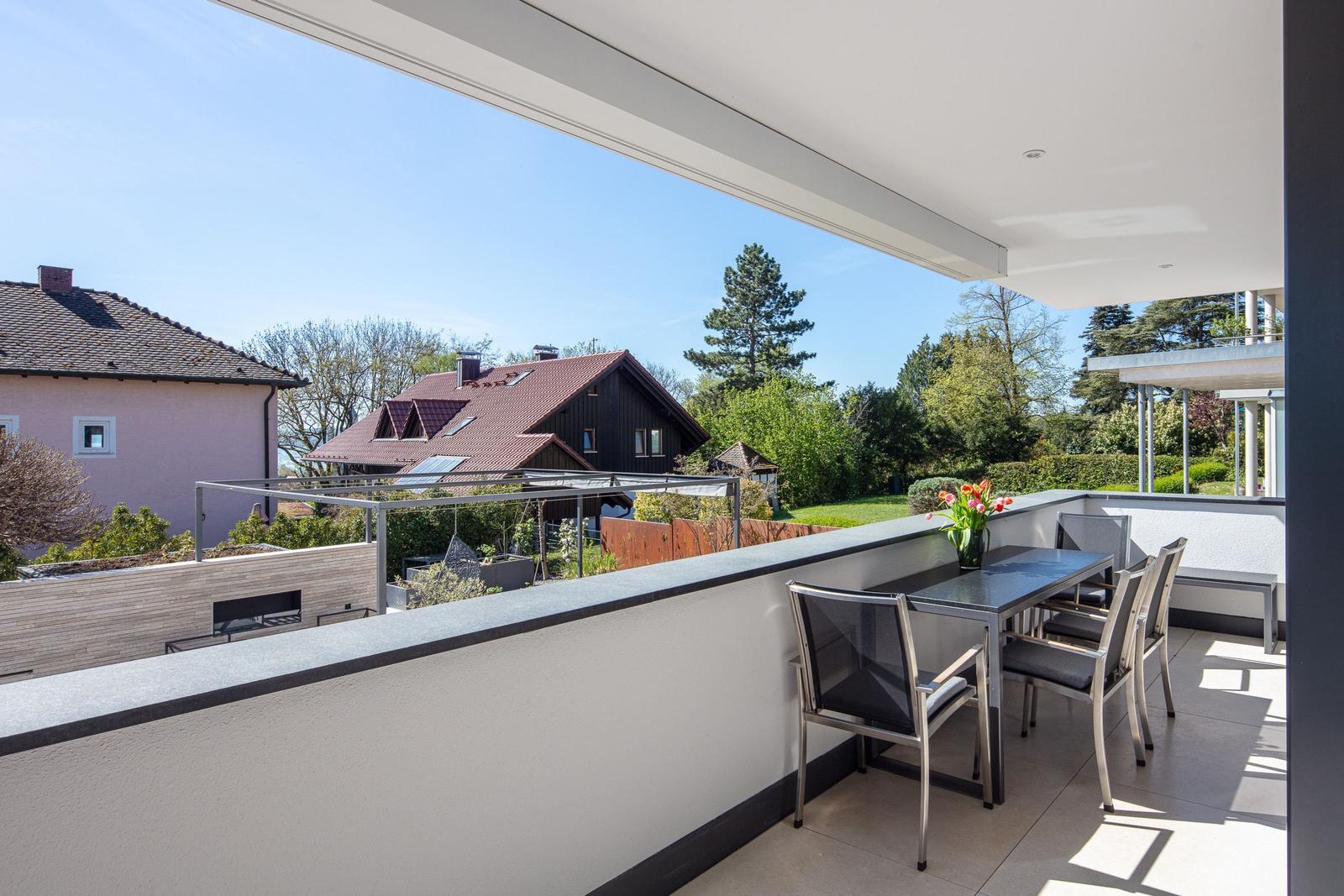 Terrasse mit Tisch und Stühlen, Blick auf Garten und Nachbarhäuser.