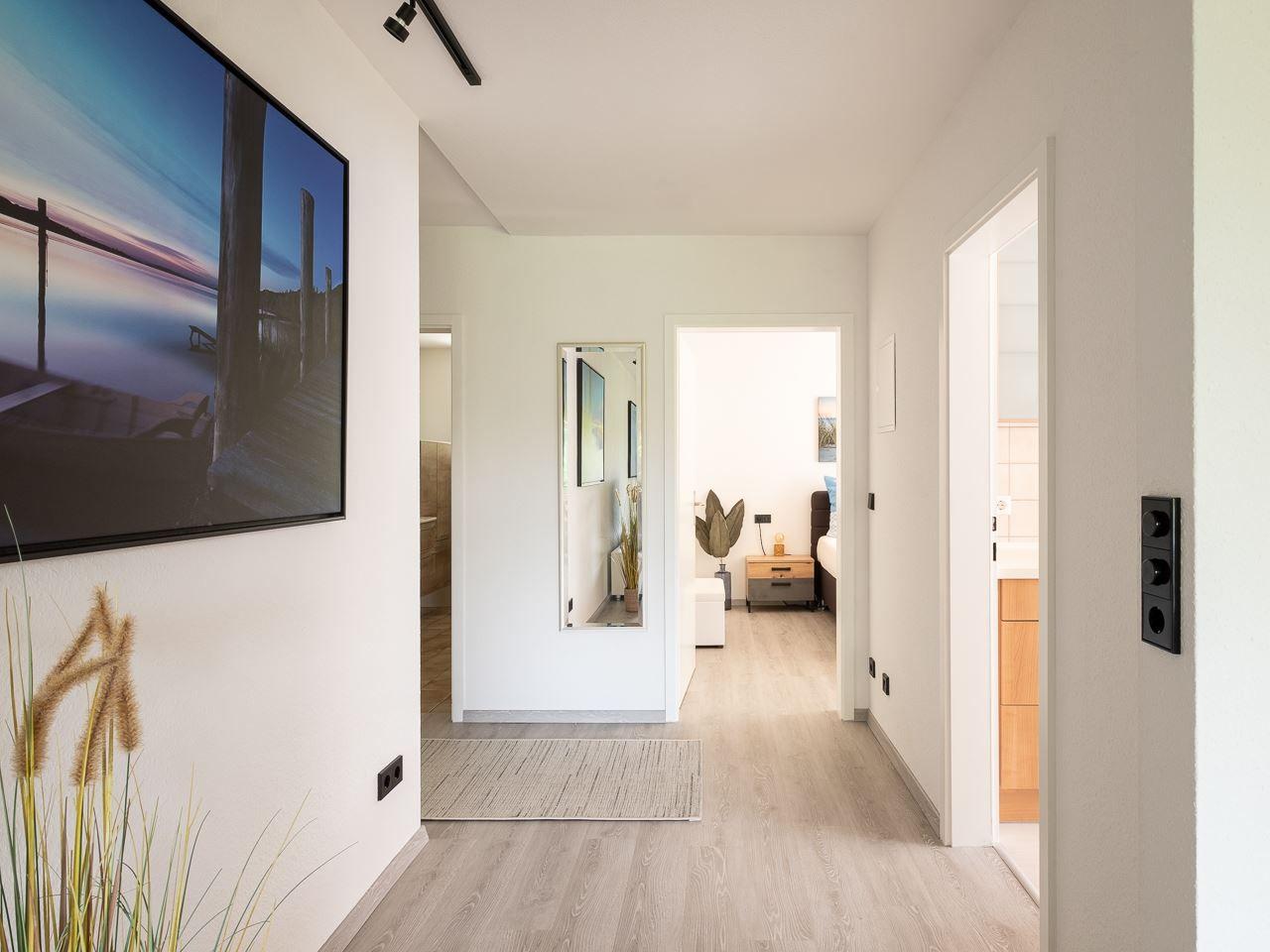 Flur mit Wandbild, Spiegel und Blick in Schlaf- und Badezimmer.