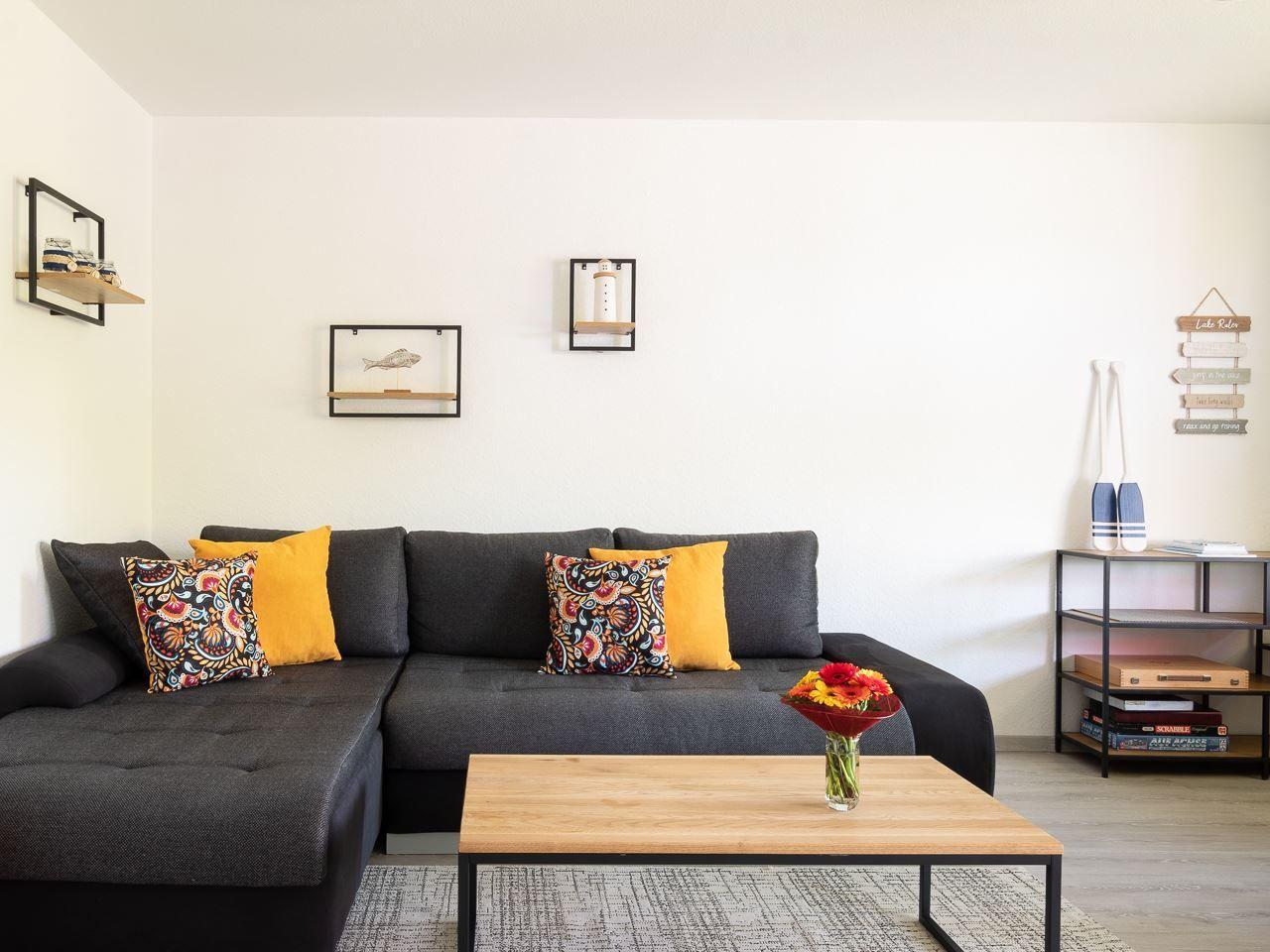 Schwarzer Sofa mit Kissen, Holztisch und Wanddekoration im Wohnzimmer.