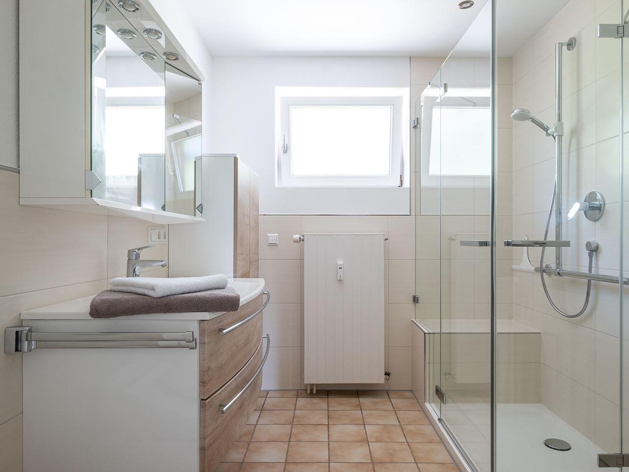 Badezimmer mit Dusche, Waschbecken und Fenster