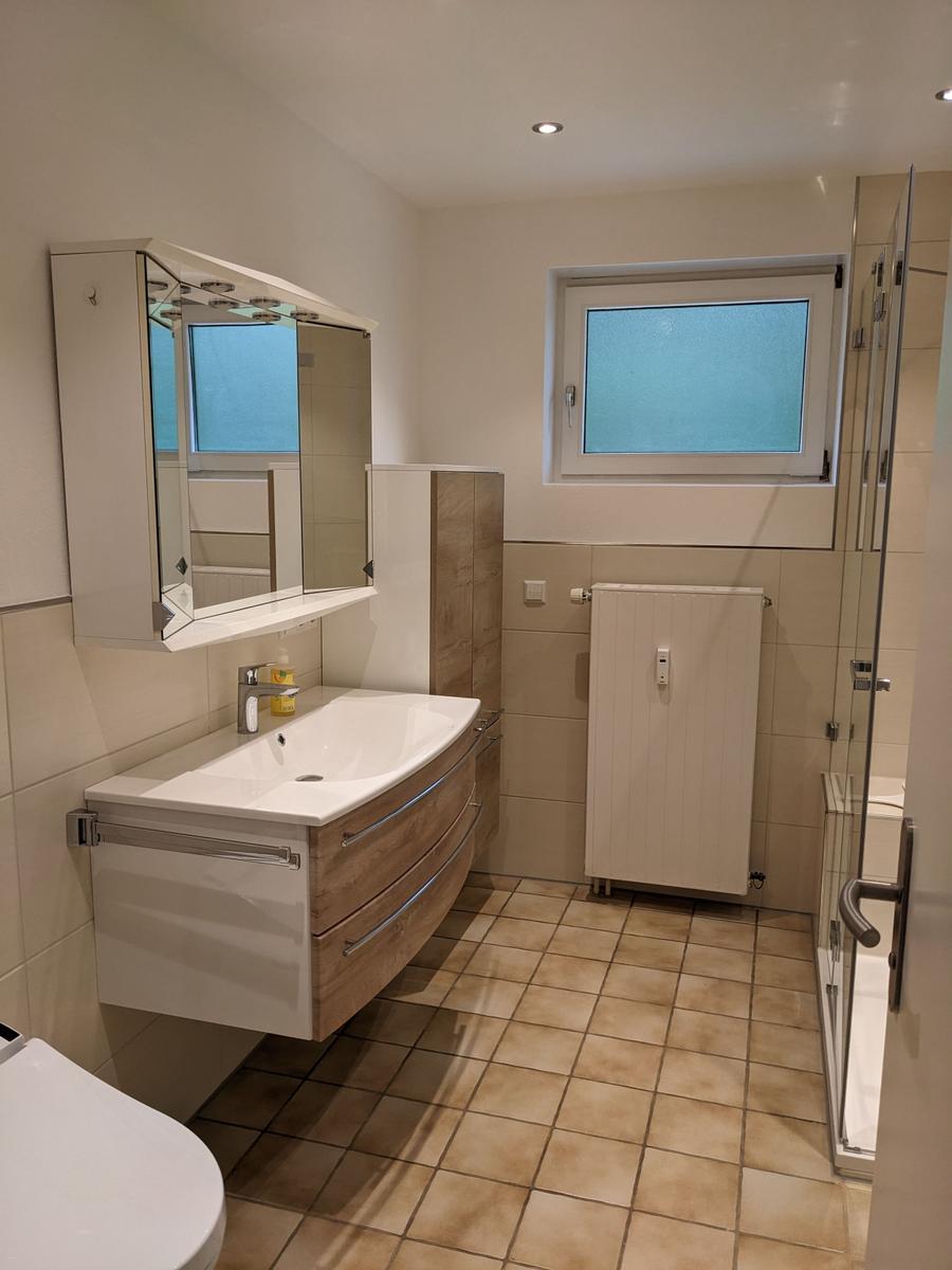 Badezimmer mit Waschbecken, Spiegelschrank, Dusche und Fenster