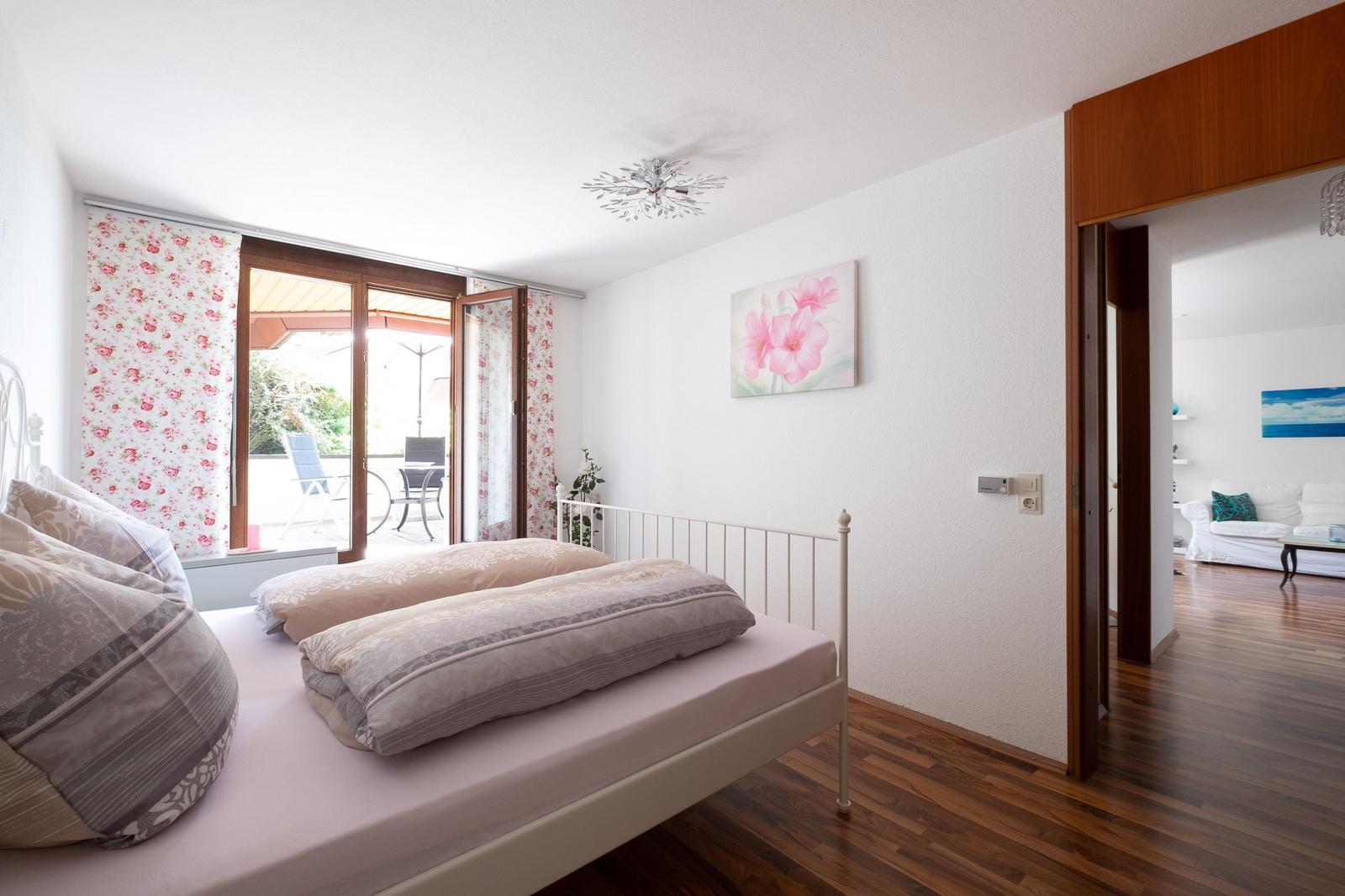 Schlafzimmer mit Bett, Balkon und Blick in Wohnzimmer