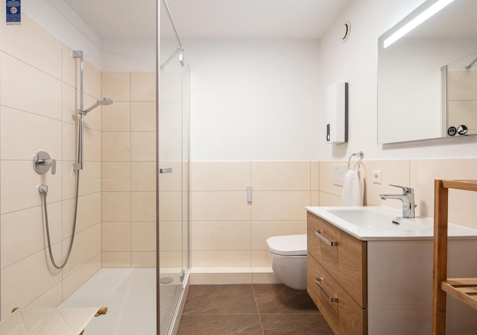 Badezimmer mit Dusche, Waschbecken und Toilette.