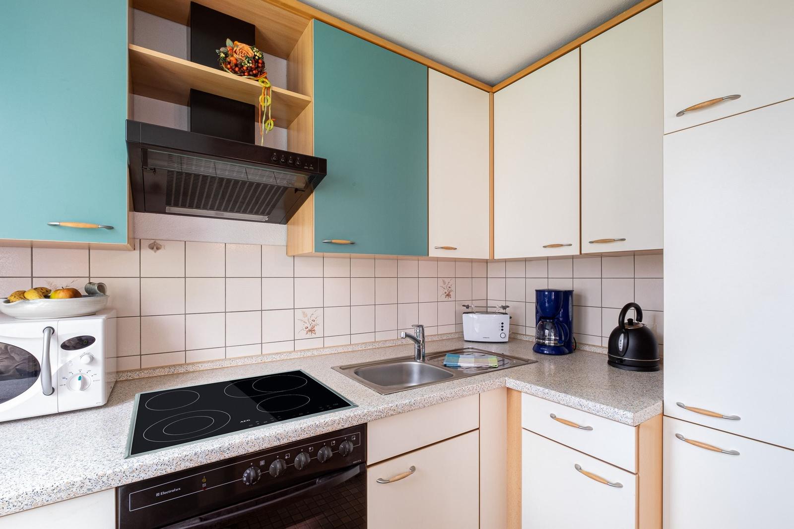 Küche mit Dunstabzug, Herd, Spüle und Kühlschrank.