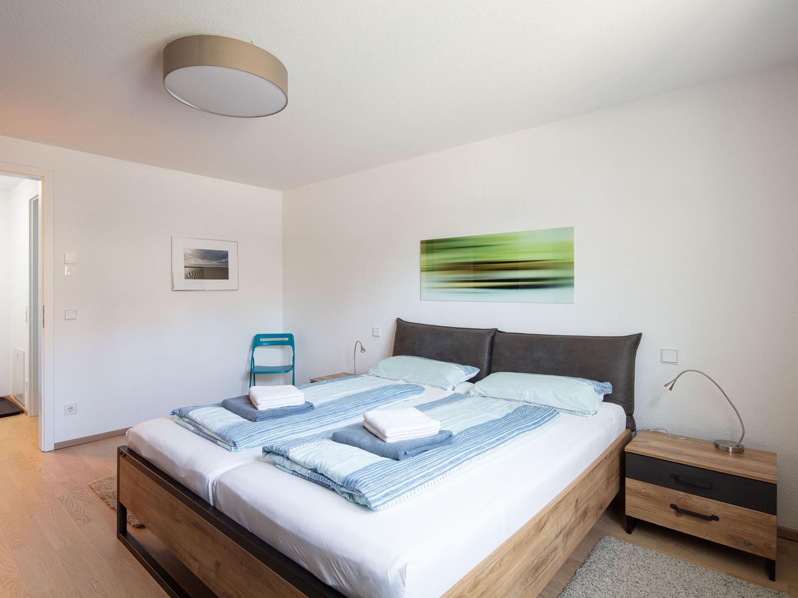 Schlafzimmer mit Doppelbett, Nachttisch und Wandbild
