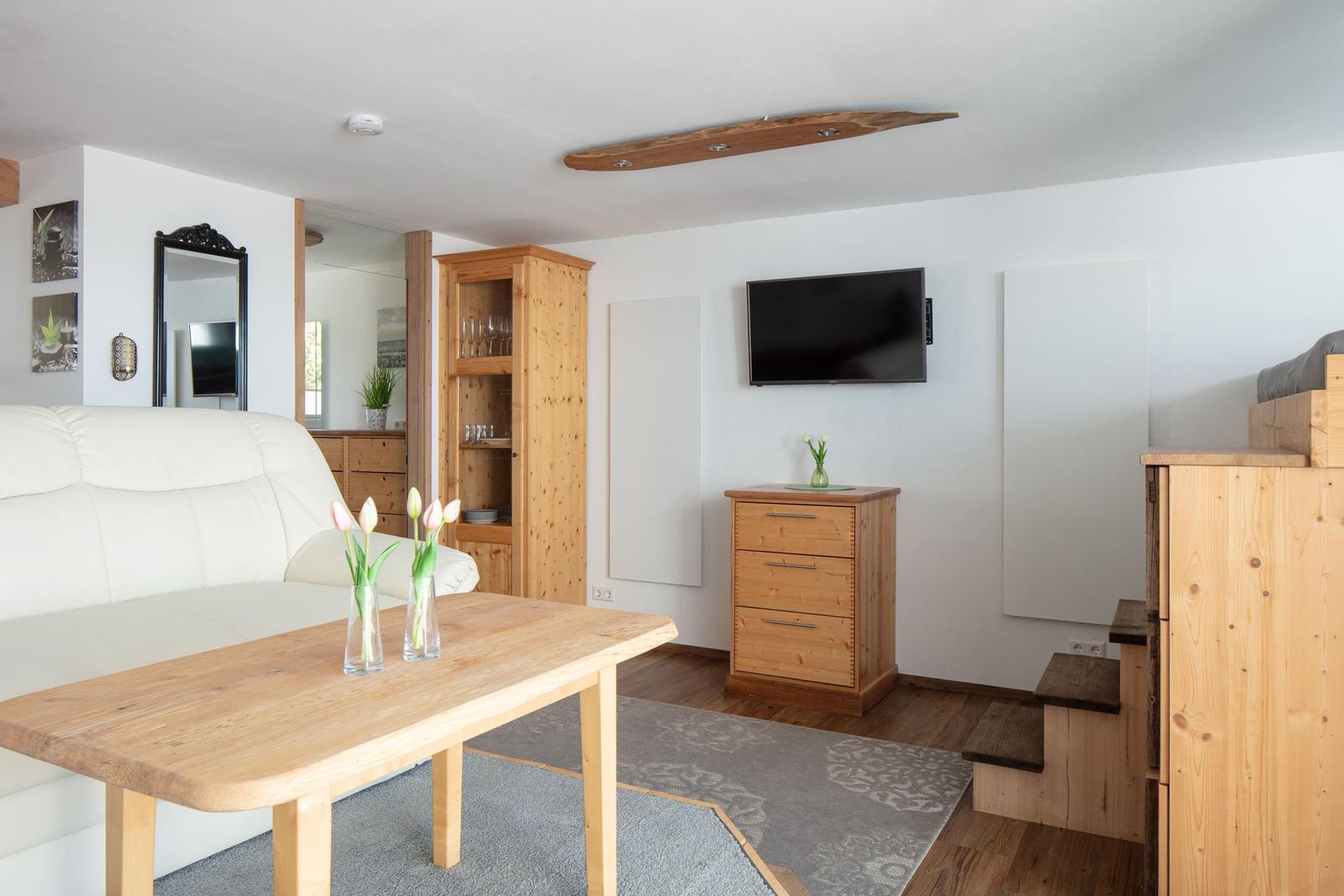 Wohnzimmer mit Sofa, Tisch, Fernseher und Holzmöbeln.