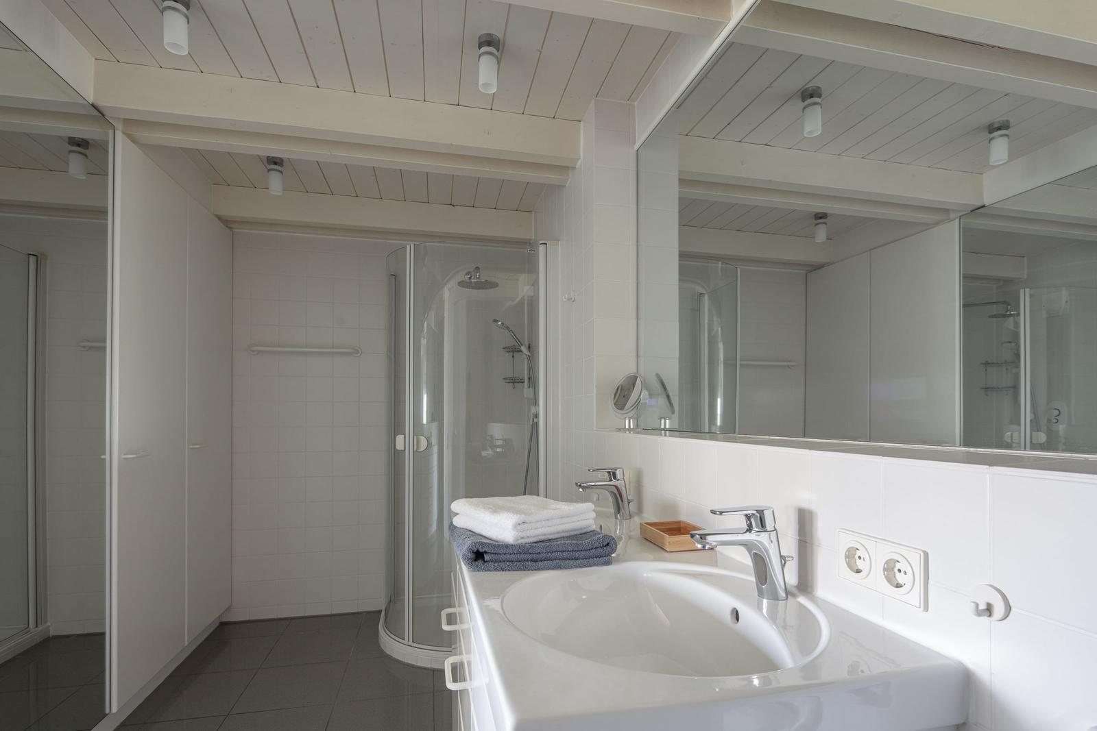 Badezimmer mit Dusche, Waschbecken und Spiegel